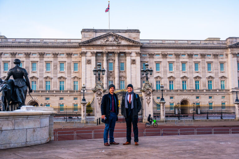 Two people posing in front of Buckingham Palace London with Union Jack flag