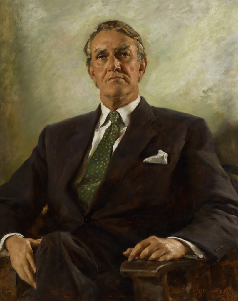 Formal portrait of a man in dark business suit, green tie, seated against neutral background