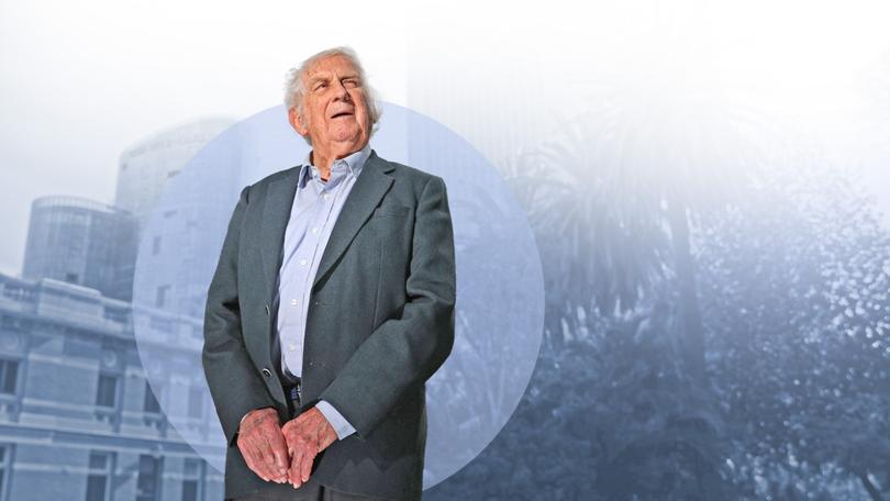 Mature man in gray blazer and light blue shirt standing against cityscape overlay background