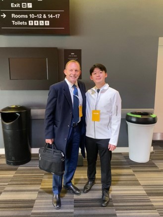 Two professionals standing together in a conference center hallway with signage visible above