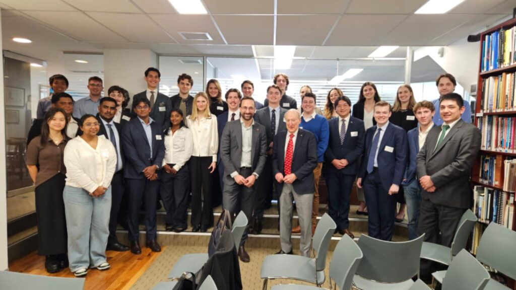 Large diverse group of professionals in business attire posed together in a modern library