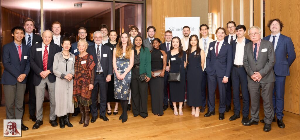 Group photo of 25 professional adults in formal business attire standing together indoors