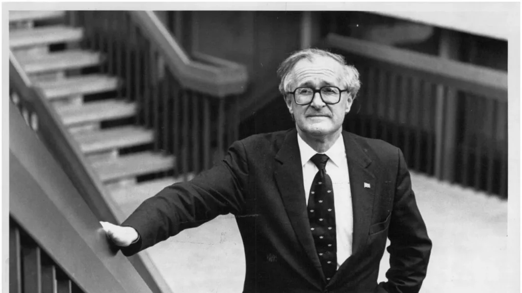 Man in dark suit and glasses standing on staircase, professional portrait style photograph